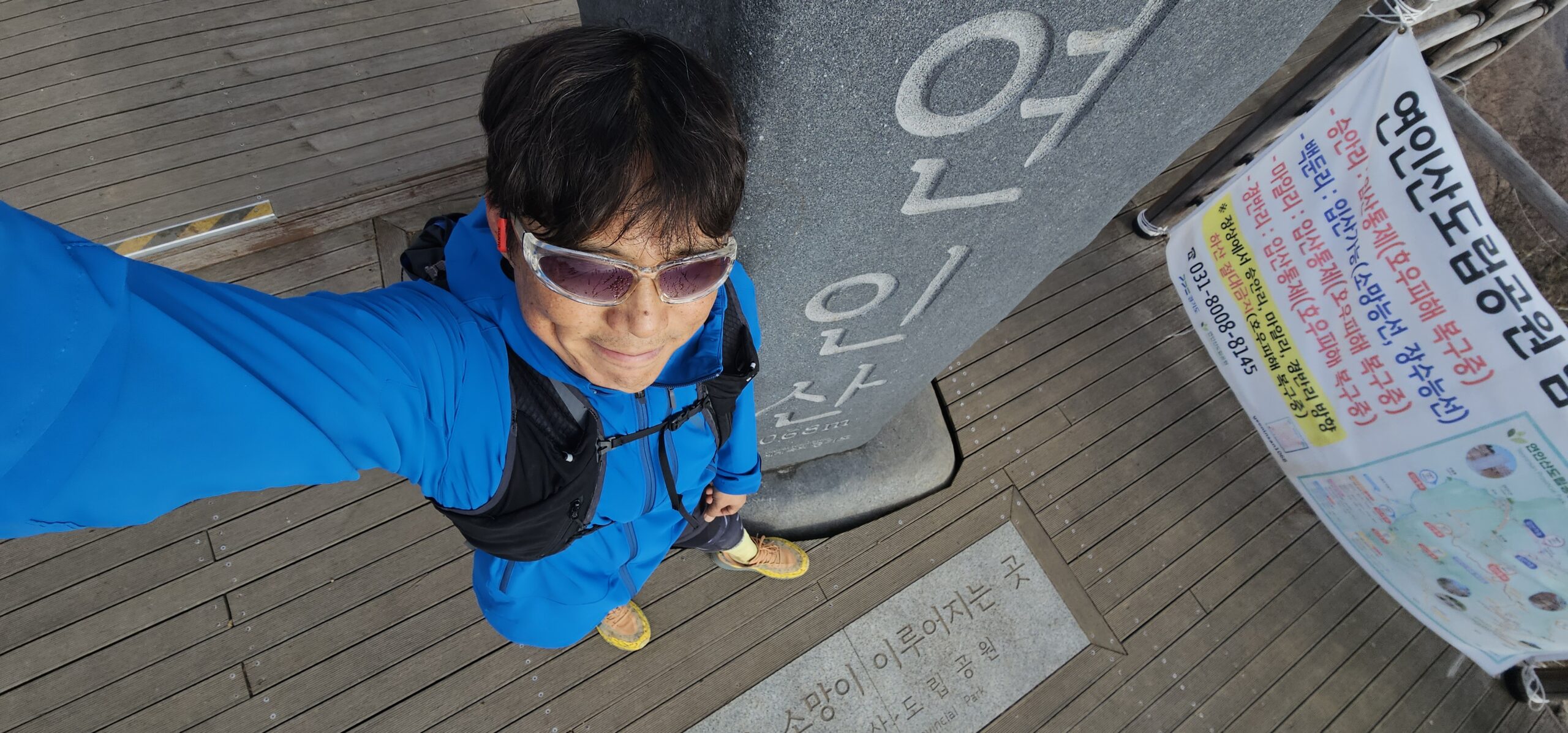 A selfie taken at the Yeoninsan summit landmark, showing the runner in blue gear standing beside the stone monument engraved with “연인산 1,068m.”